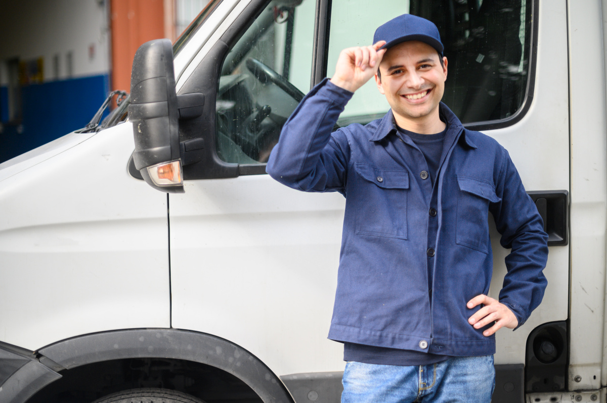 Portrait of a driver standing enar his van and smiling